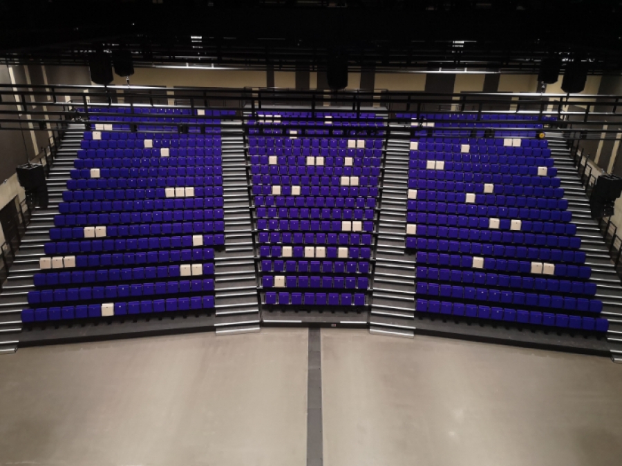 Trapezförmige Teleskoptribüne mit violetten Polstersitzen in einer Mehrzweckhalle