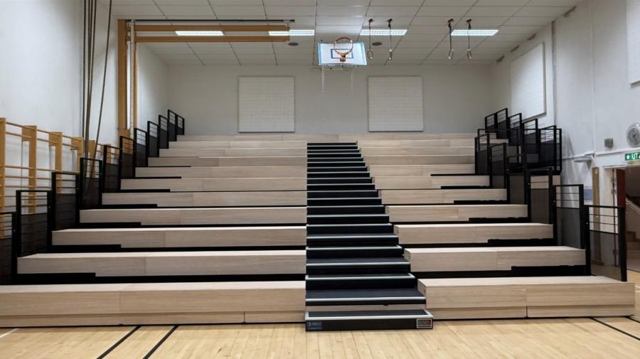 Schulsporthalle mit ausgefahrener Teleskoptribüne aus Holz-Sitzstufen