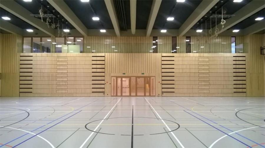 Schulsporthalle mit eingefahrener Holztribüne in der Wandnische – volle Spielfläche