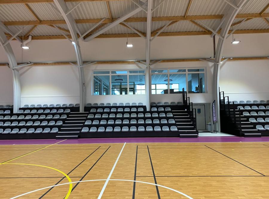 Moderne Sporthalle mit Teleskoptribüne und grauen Sitzschalen