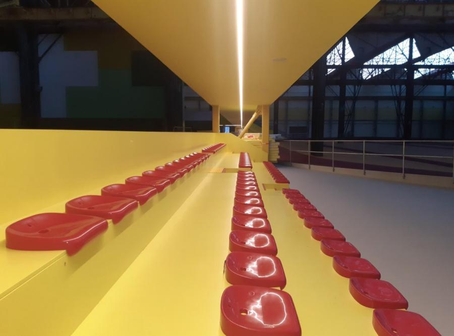 Tribüne mit roten Sitzschalen in einem Sportkomplex