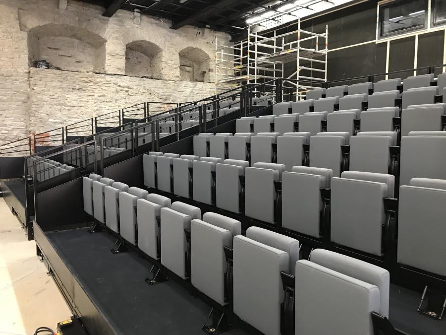 Theater in historischem Steingebäude mit grauen Polstersitzen auf Teleskoptribüne